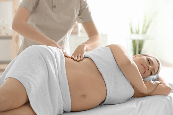 Una mujer realizándose un masaje de espalda para cuidar su embarazo.